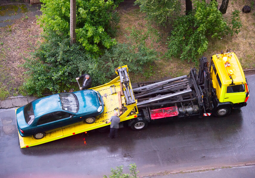 Loading broken car on a tow truck on a road. Aerial view